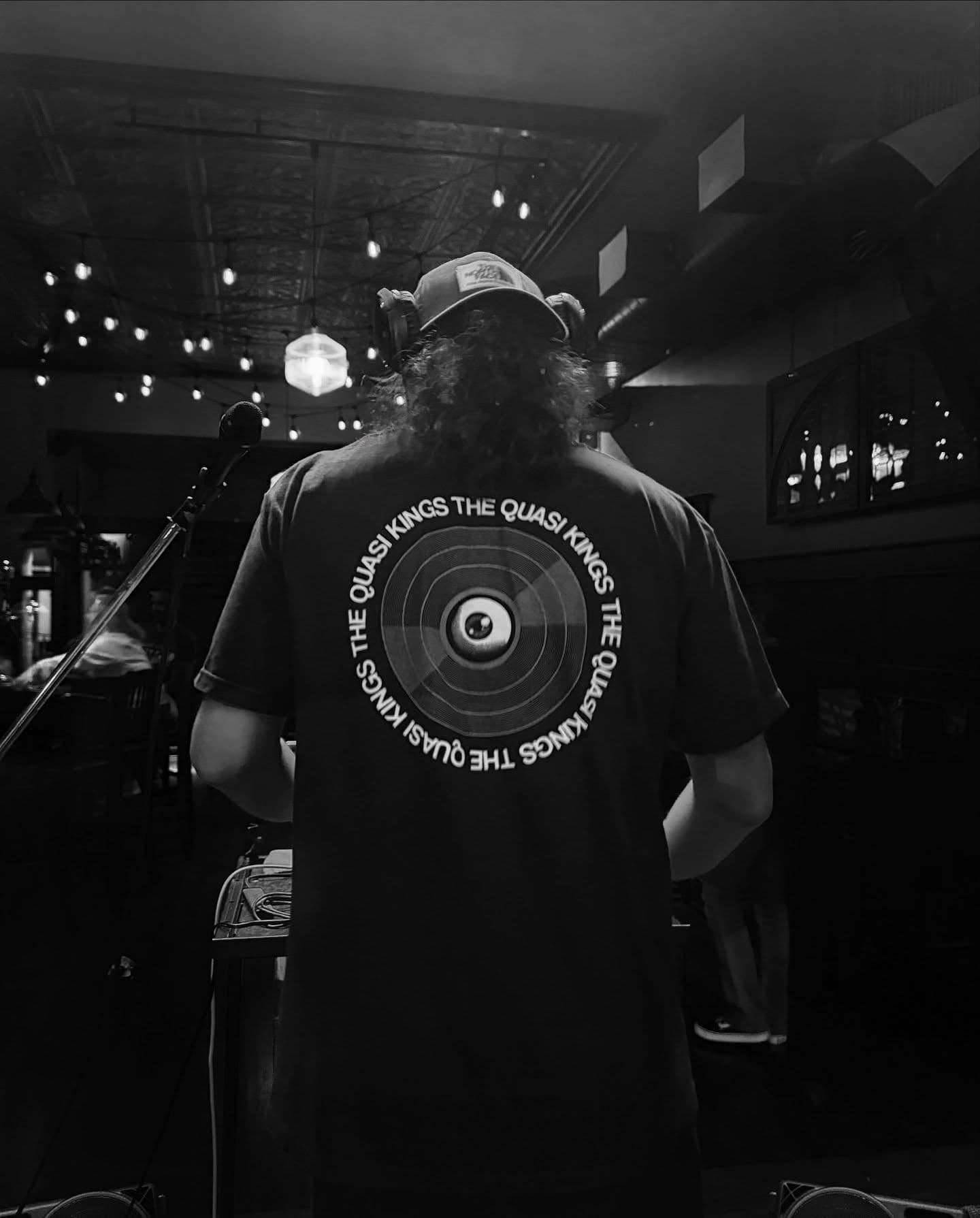 DJ Maxafari at the decks in a bar, seen from behind