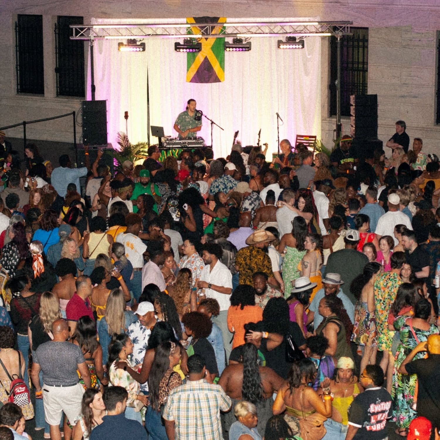A packed crowd dancing in front of DJ Maxafari's stage, with a Jamaican flag above the decks